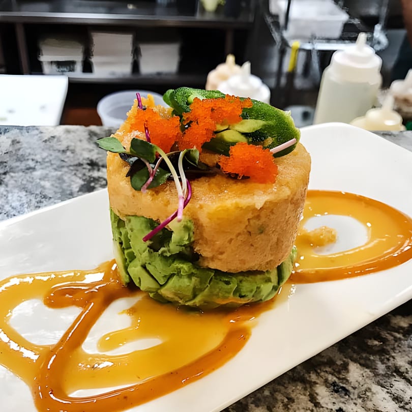 Itto Ramen Bar Tapas' tuna tower with avocado, tobiko, and microgreens, drizzled with sauce.